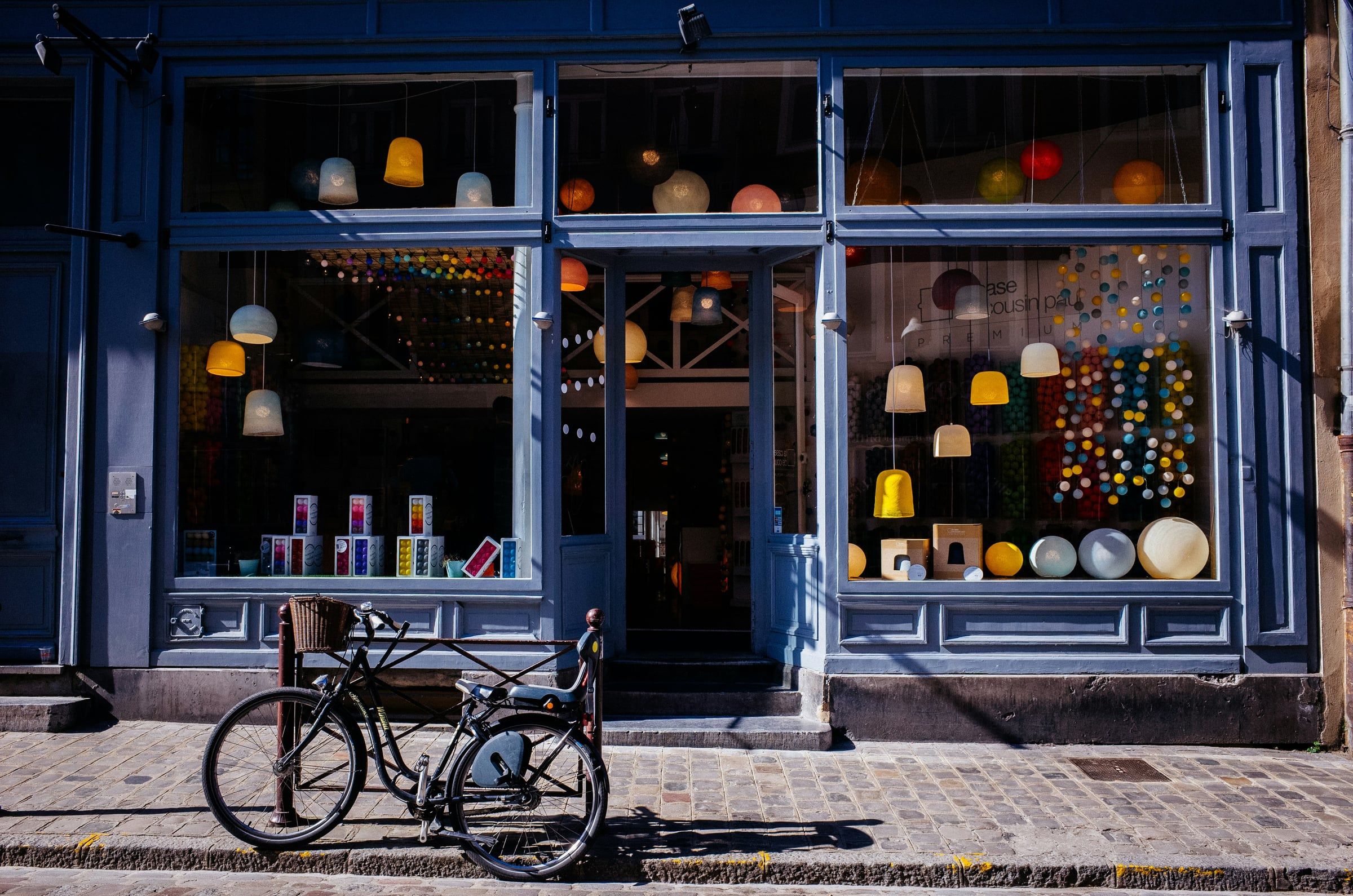 Devanture bleue d'une boutique de luminaires, un vélo garé sur le trottoir