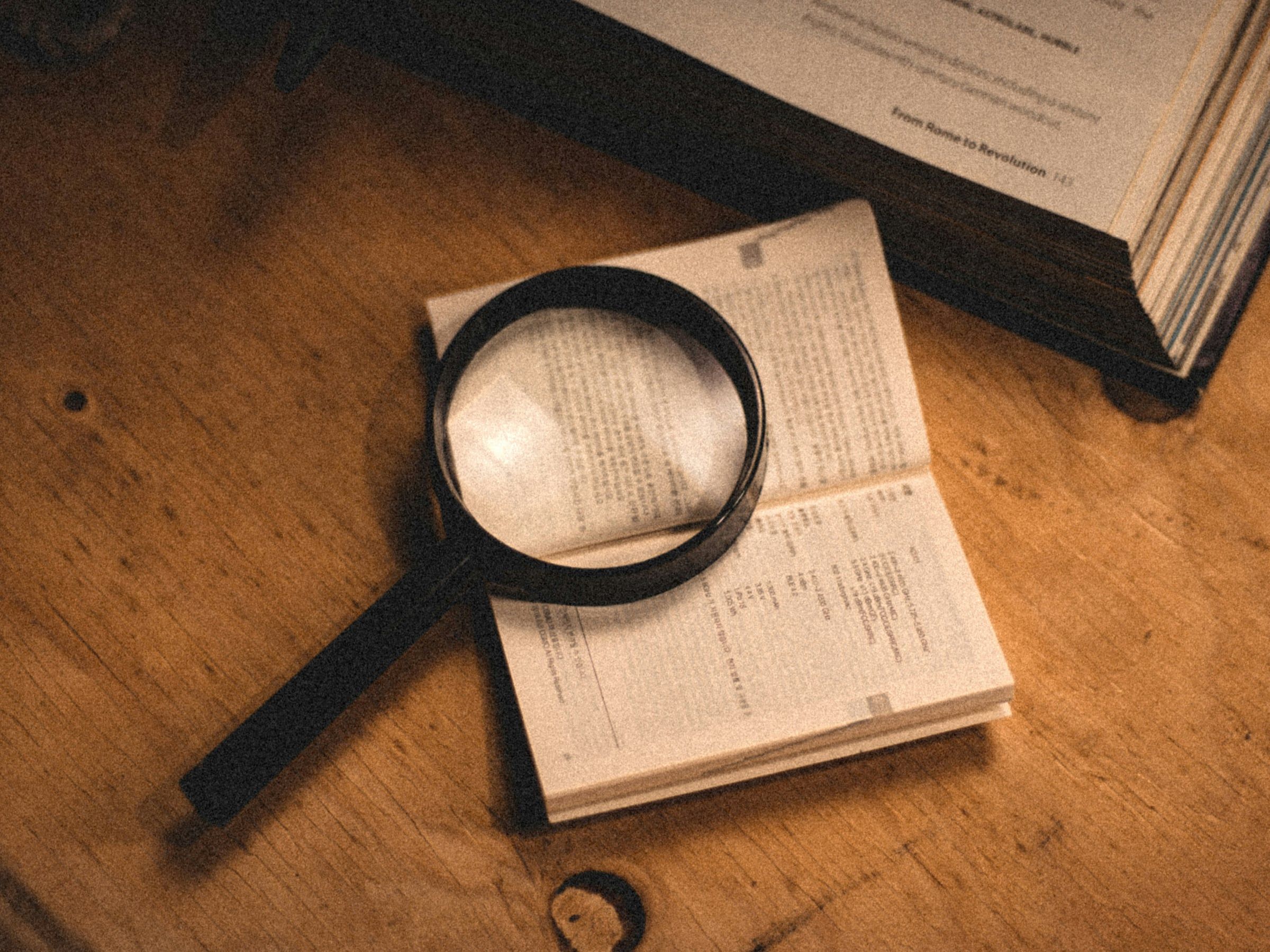 Une loupe posée sur un livre ouvert, sur une table en bois
