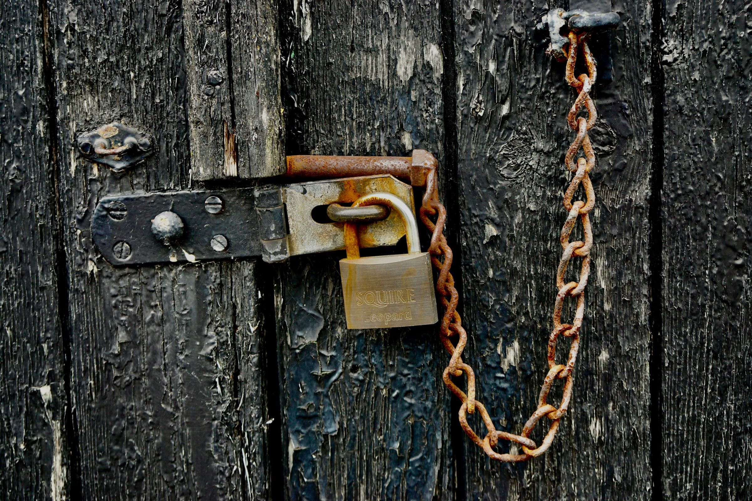 Un cadenas et une chaîne rouillée sur une vieille porte en bois